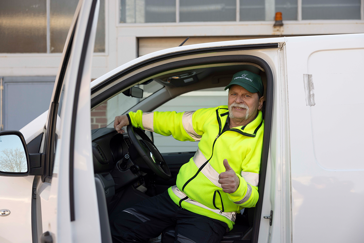 Fahrer von Vielfaltmenü sitzt am Steuer eines Lieferfahrzeugs und zeigt mit der Hand ein positives Daumenzeichen.